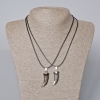 Twin pendants 'Fang' with black enamel and silvery metal, 35×12 mm; length 45–50 cm